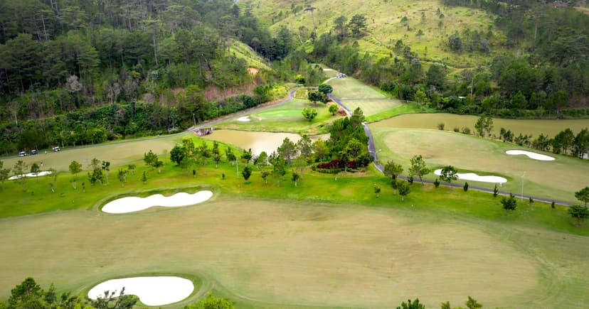 Aerial view of a lush green golf course set in a valley with trees