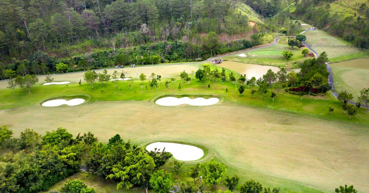 Aerial view of a golf course with tropical trees and sand bunkers